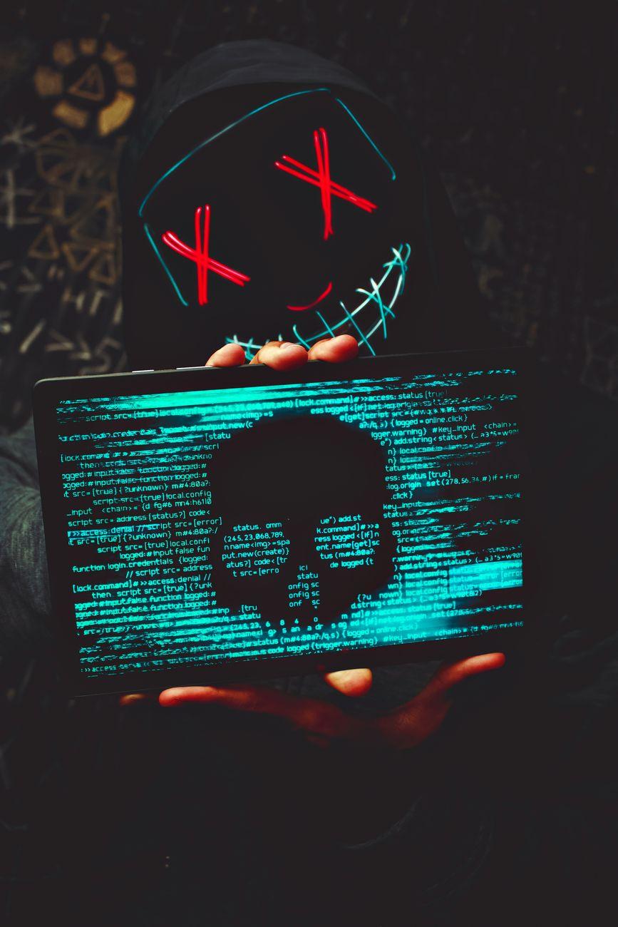 a person wearing mask with neon lights holding a tablet with skull image
